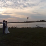 Newlyweds kissing in front of the sunset and water